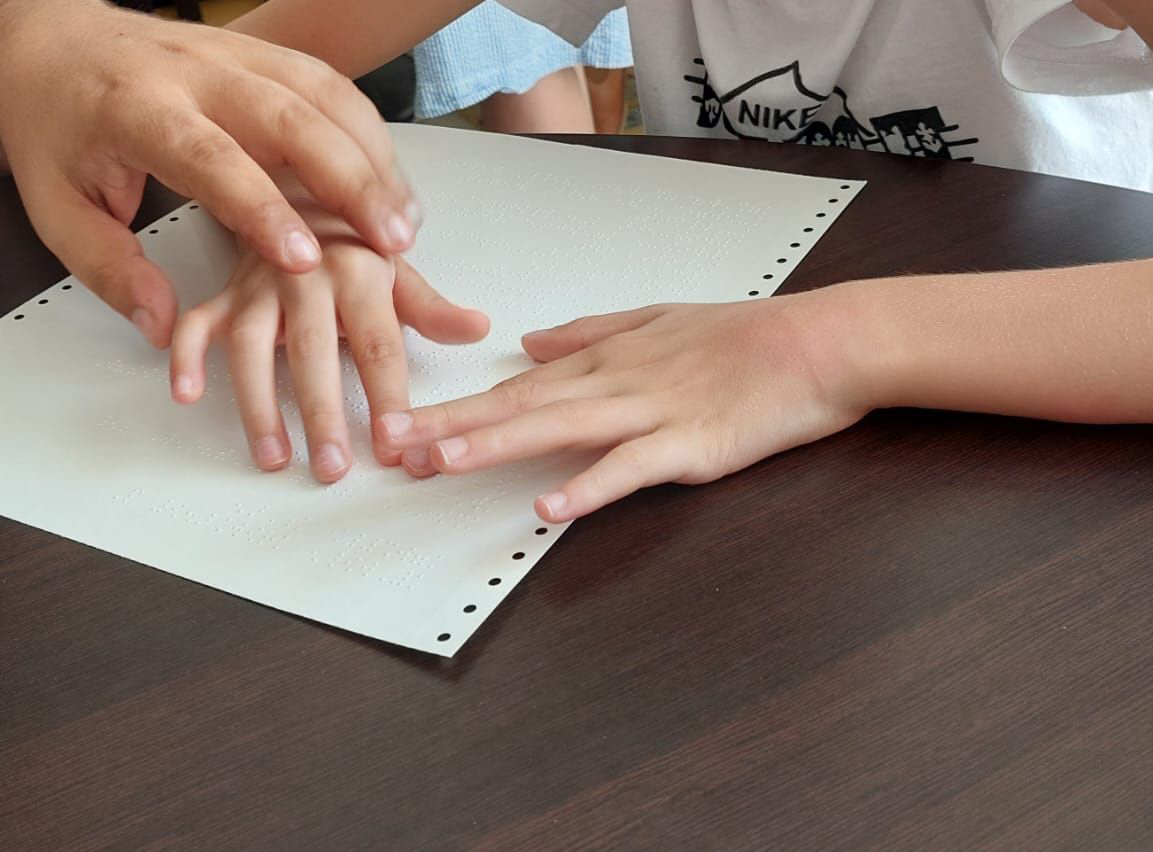 Lettura di un foglio scritto in braille da parte di un bambino